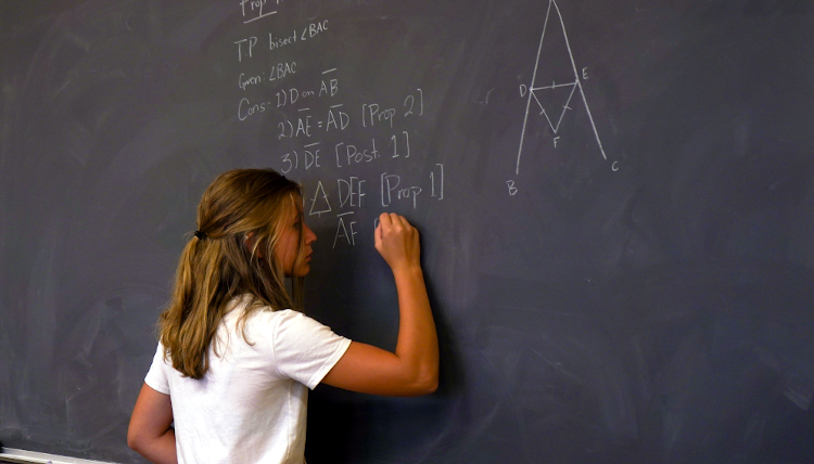 Student works on a prop at the blackboard