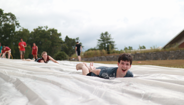 A smiling student speeds down the slide