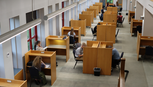 Students at individual desks study in the lower floor of the library