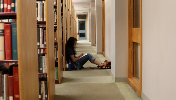 A student studies in a quiet corner amid the bookshelves