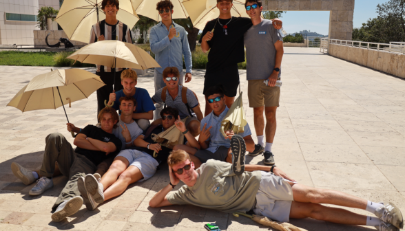 Several pose for a photo under sunbrellas