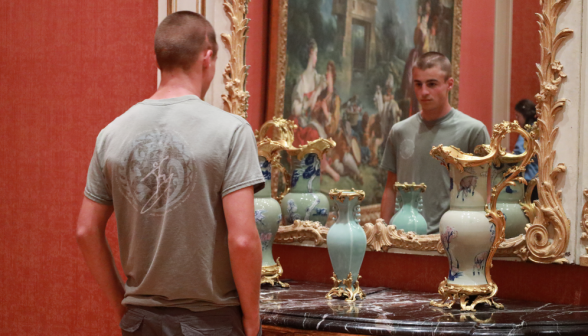 A student before an ornate miror and matching vase and pitcher collection