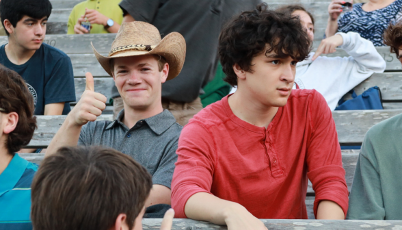 A student in a cowboy hat gives a thumbs up