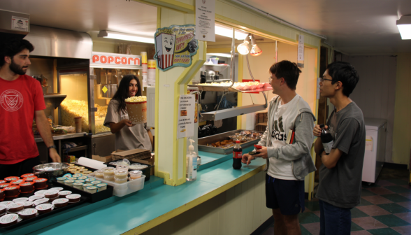 A snack shop worker serves popcorn to a student