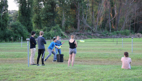 Students play frisbee while others look on