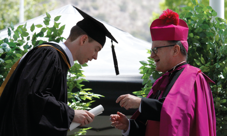 Bishop Barber presents a diploma to a member of the Class of 2020