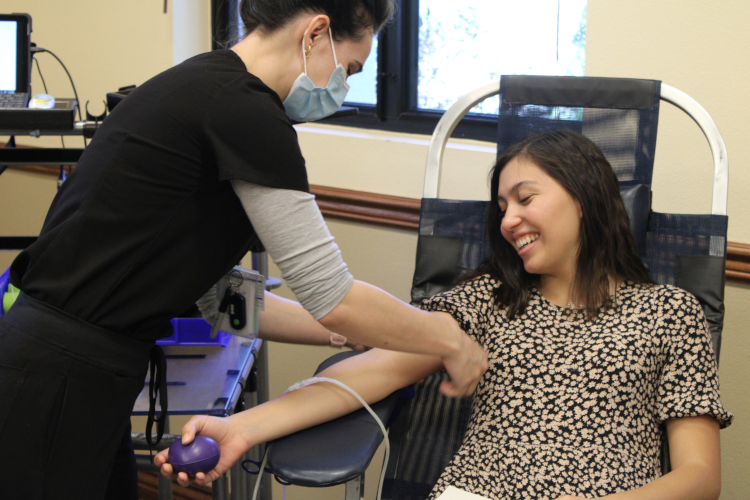 The nurse prepares a smiling student to have blood drawn