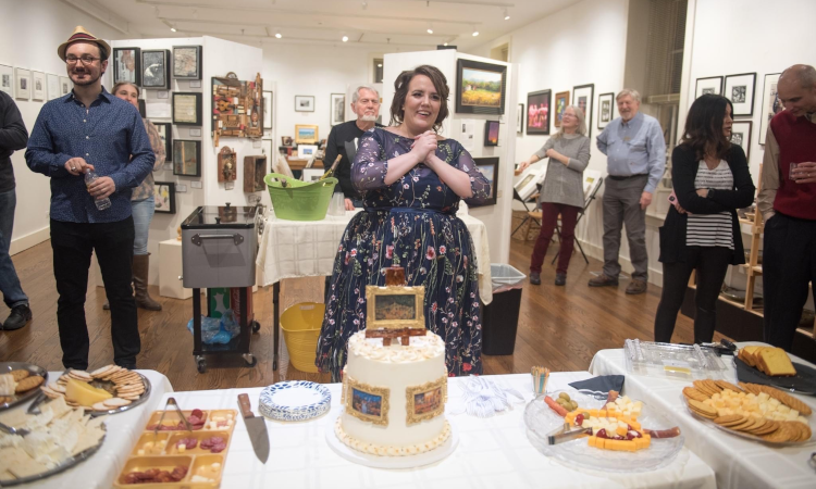 Ms. Claahsen behind a table of foods at an art exhibition