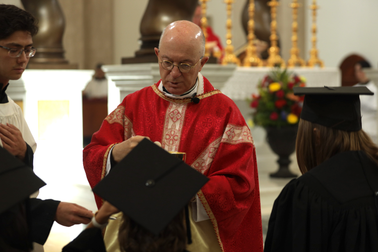 Fr. Mata administers Communion to the graduates