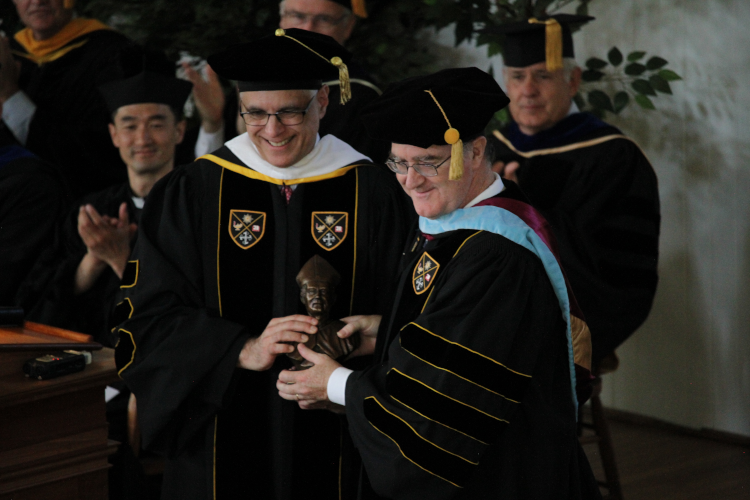 Chairman of the Board of Governors Scott Turicchi presents a bust of St. Albert the Great to Daniel T. Flatley at New England Commencement 2023