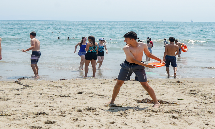 A student at the water's edge getting ready to throw the Frisbee
