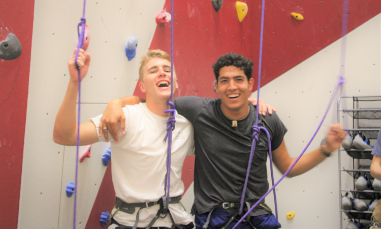 Two students pose for a photo at the rock-climbing wall