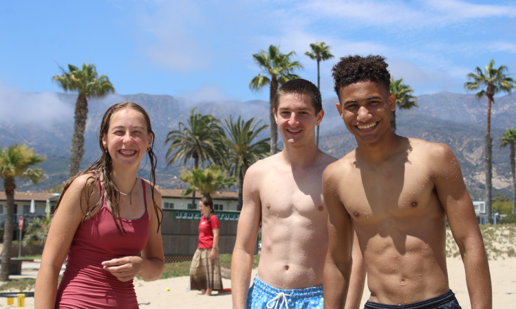 Three students pose for a photo at the beach