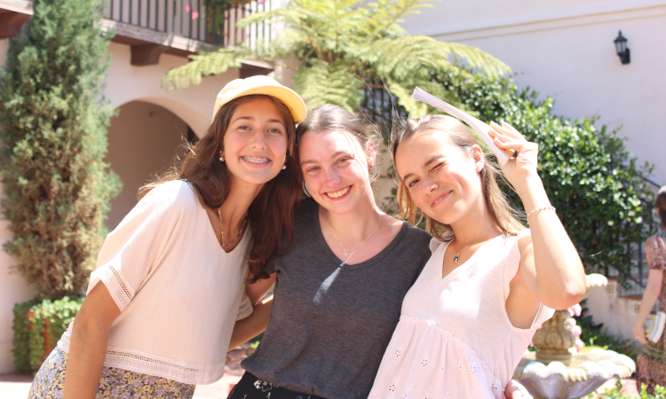 Three pose for a photo outside the dorm