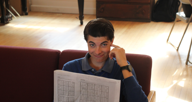 A student looks up from reading the newspaper in the Commons