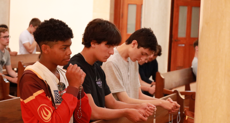 Three in a pew praying the Rosary