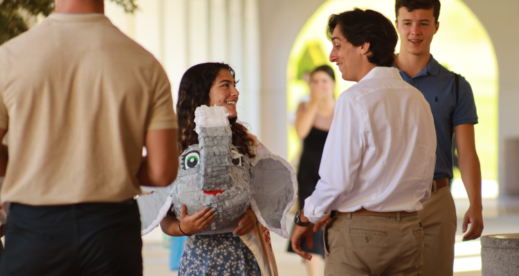 A student admires the severed elephant head from last night's pinata, carried by another student