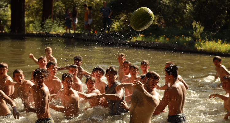 Students in the pond throw the volleyball