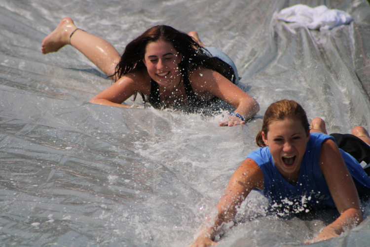 Two students slide down the slip n' slide