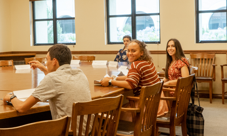 Students await the start of class around the seminar table