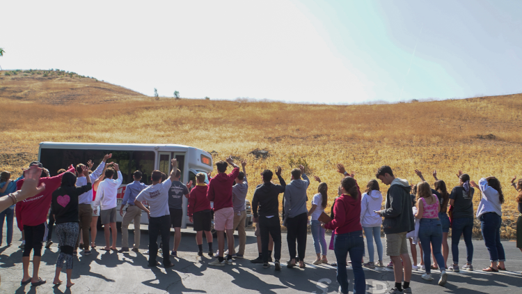 Students wave goodbye to a dpearting bus