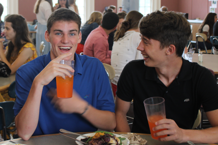 Two students laughing over orange soda and chicken