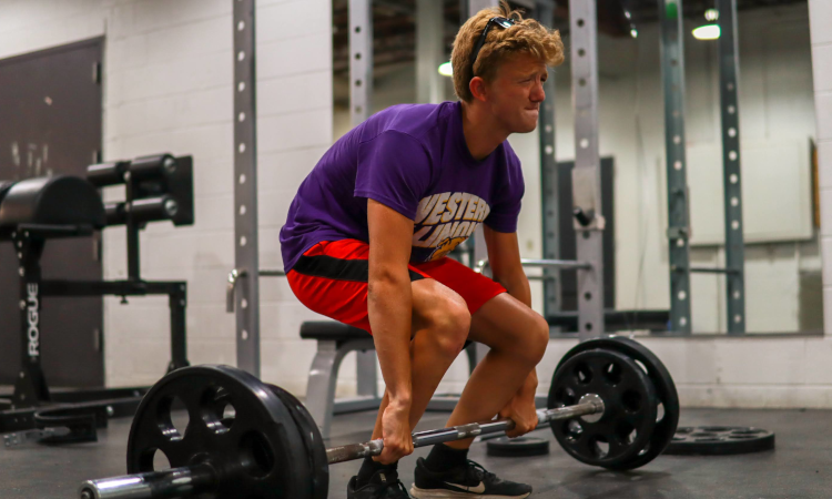 A student grimaces while deadlifting