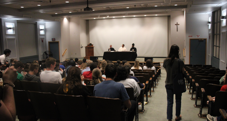 The three priests answer theology questions at a table in the auditorium