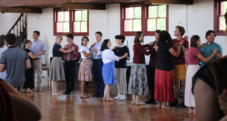 Student pairs listen to the dance instructor