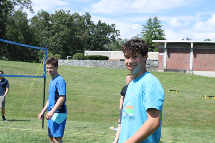 Students playing volleyball pause to smile at the camera