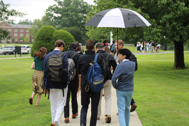 Students walk across campus under an umbrella