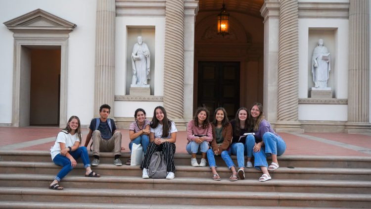 A group of eight students, seated on the Chapel steps