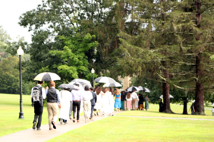 Students walk across campus under umbrellas