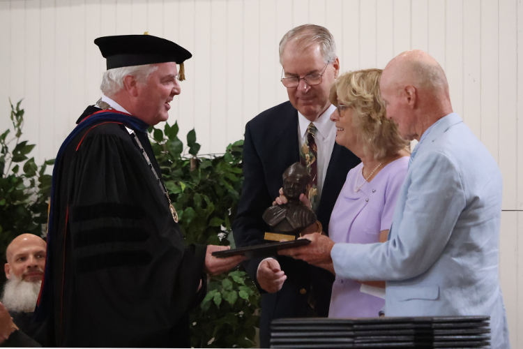 College President Paul J. O’Reilly presents a bust of St. Albert the Great to Alice and Hank Graebe and Vincent Smith, family members of Eugene F. Horan.