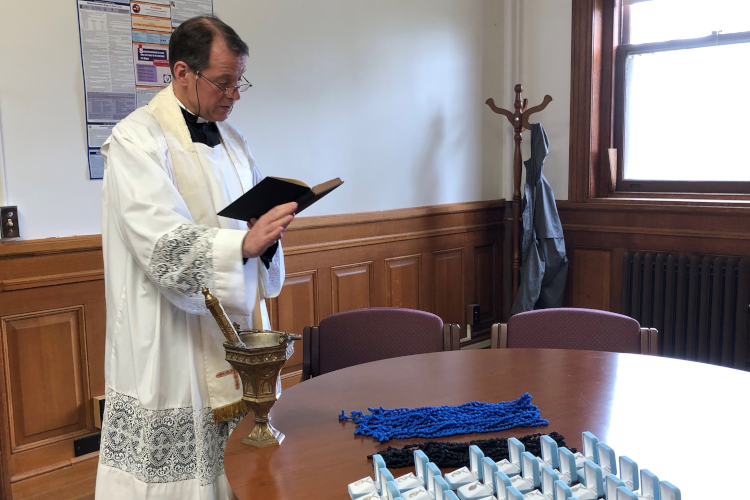 Photo: NE blessing, with caption: … and his counterpart, Rev. Greg Markey, blesses the medals and Rosaries in New England.