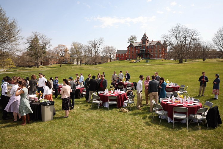 With the Class of 2024 nearing Commencement, members of the New England Class of 2026 recently took the opportunity to thank the seniors for their example and friendship at the annual Sophomore-Senior Brunch. After morning Mass on Sunday, seniors and sophomores headed down to the field in front of Dolben Library, for an outdoor feast. Tables were decorated with flowers from around campus, and the morning sun warmed the event’s cheery atmosphere. Before sitting down, seniors mingled with sophomores over coffee and orange juice, chatting about the curriculum and plans for the summer.  Brunch consisted of deconstructed egg sandwiches: bagels, scrambled eggs, and bacon, accompanied by colorful platters of fruit at each table. Toward the end of the meal, as people refilled their coffee, the toasts began. Many students toasted both classes: Sophomores thanked seniors for their kindness and assistance, while seniors thanked sophomores for their enthusiasm and love for the TAC education. “I’d like to thank the Senior Class for your example,” said Duarte de Lima (‘26). “You all have stood as good beacons to follow throughout our time here, especially in fostering the spiritual life on campus.”  The Sophomore-Senior brunch is the first of several commemorative events with which the College community sends off the graduating class. In their turn, the juniors, freshmen, and faculty will have the chance to thank the Class of 2023 for its contributions and wish its members well on future endeavors.