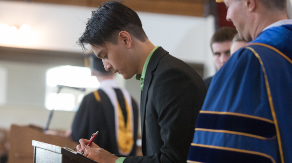 A student signs the register at Matriculation