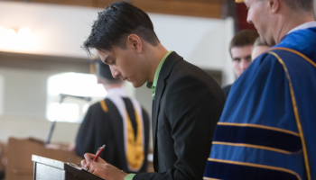 A student signs the register at Matriculation