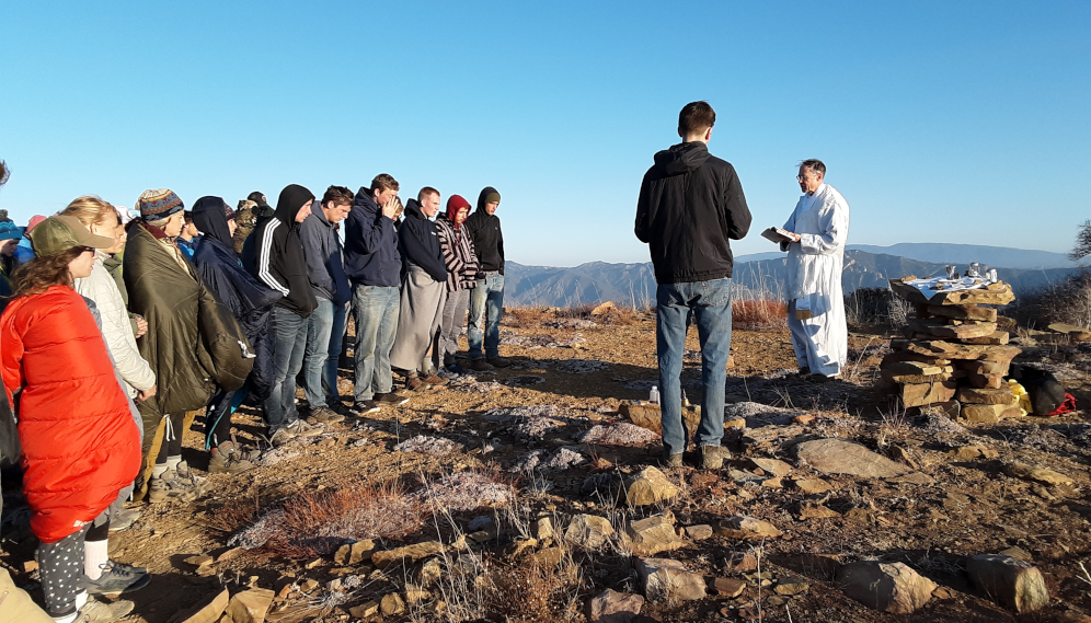 Fr. Paul reads the Gospel to assembled students on a hiking trip