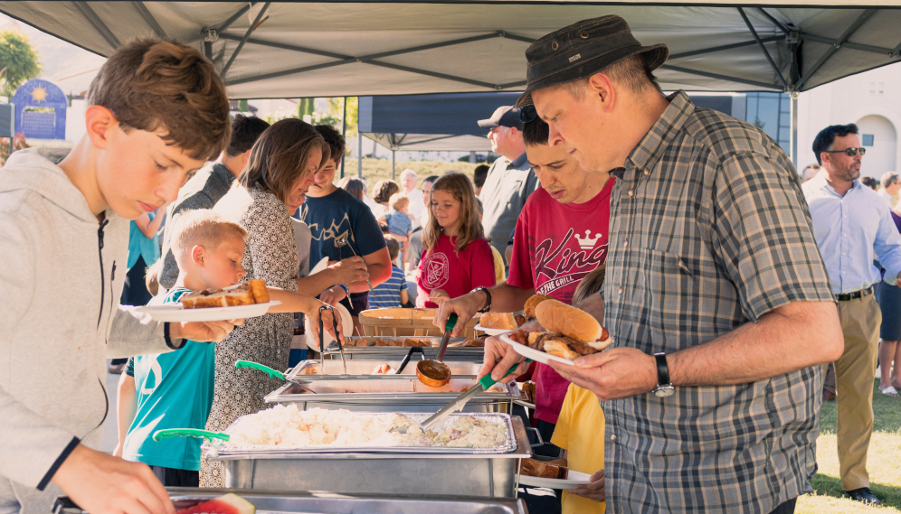 Tutors and families get food at the outdoor lunch buffet