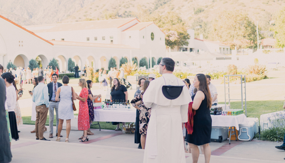 Various groups of alumni chat around the drinks table