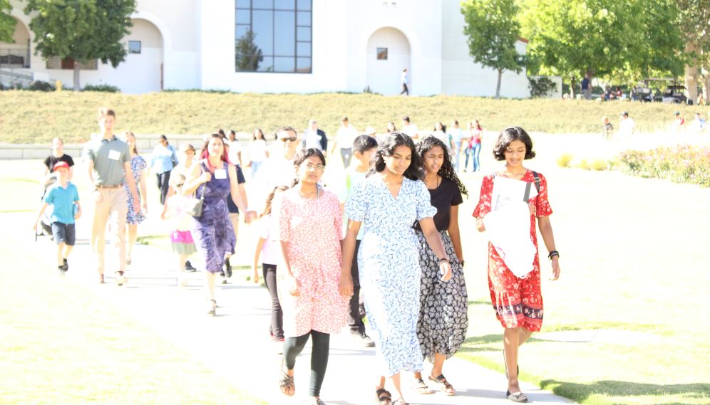 Amidst bright sunlight, the summer programmers and their families walk down to the gym and athletic field