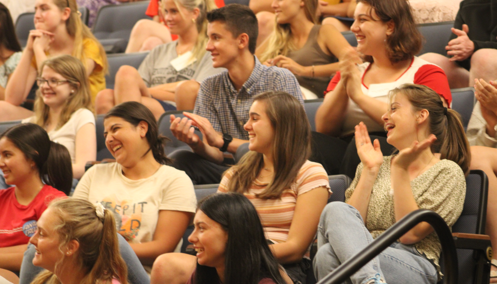 Students in the auditorium seating laugh and applaud