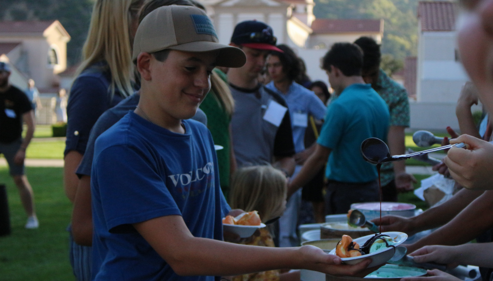 A brother of a freshman receives a scoop of chocolate sauce