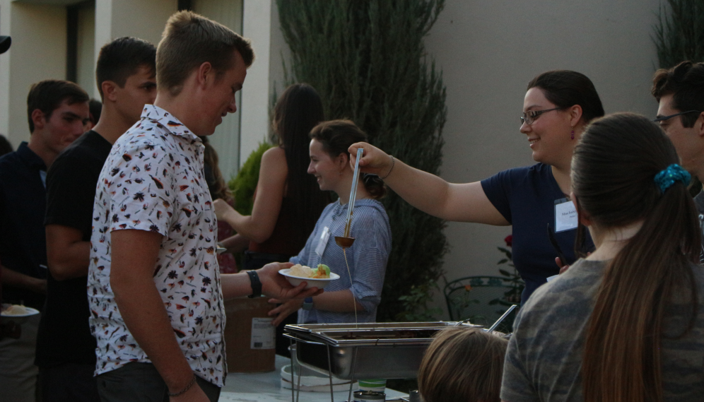 A student receives a scoop of caramel sauce
