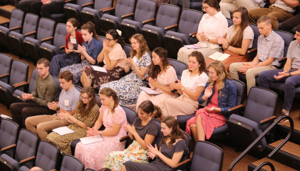 Students in the chairs applaud