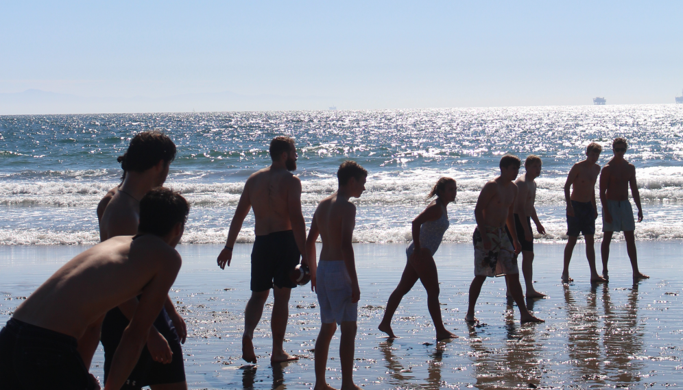 A line of students by the water, which sparkles with the sun's reflection