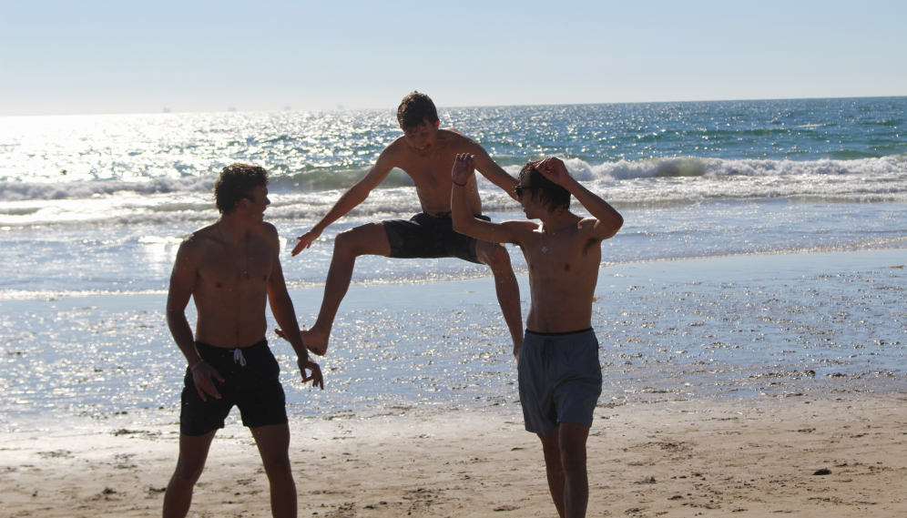 A student in mid-leap behind two of his friends