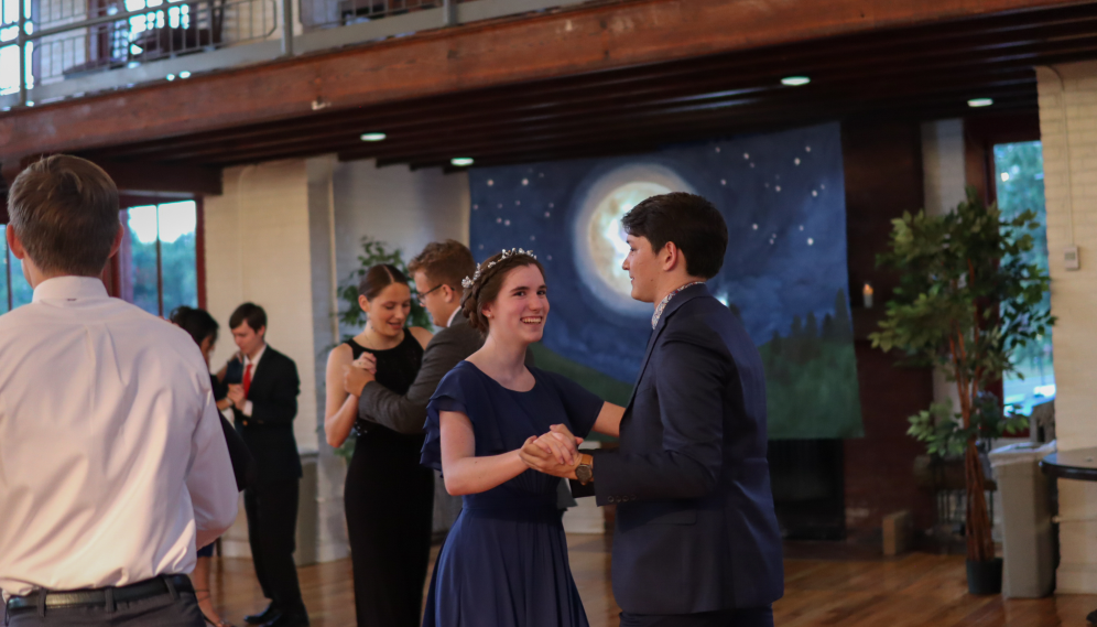 Student pairs in waltz position afront a starry night backdrop