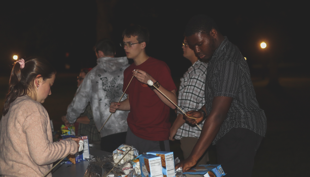 Students spear marshmallows for roasting